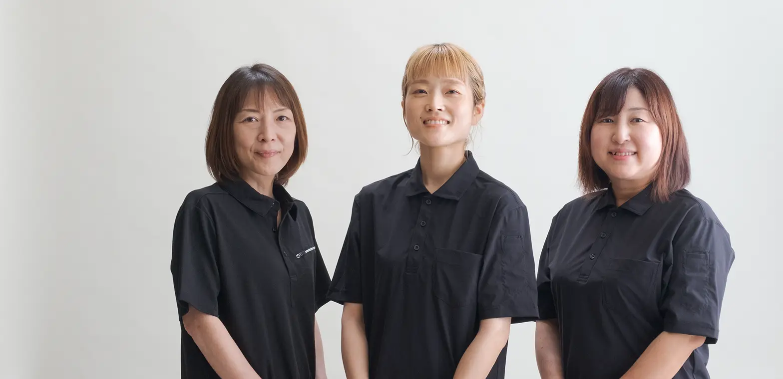 黒いポロシャツの制服を着た明るい雰囲気の社内スタッフ集合写真