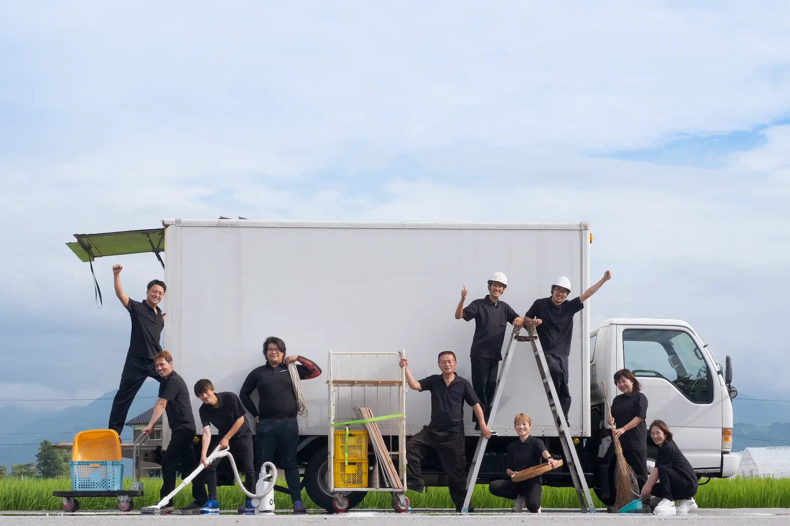 AMADOI作業員の集合写真 トラックと作業道具を持つ笑顔のスタッフ