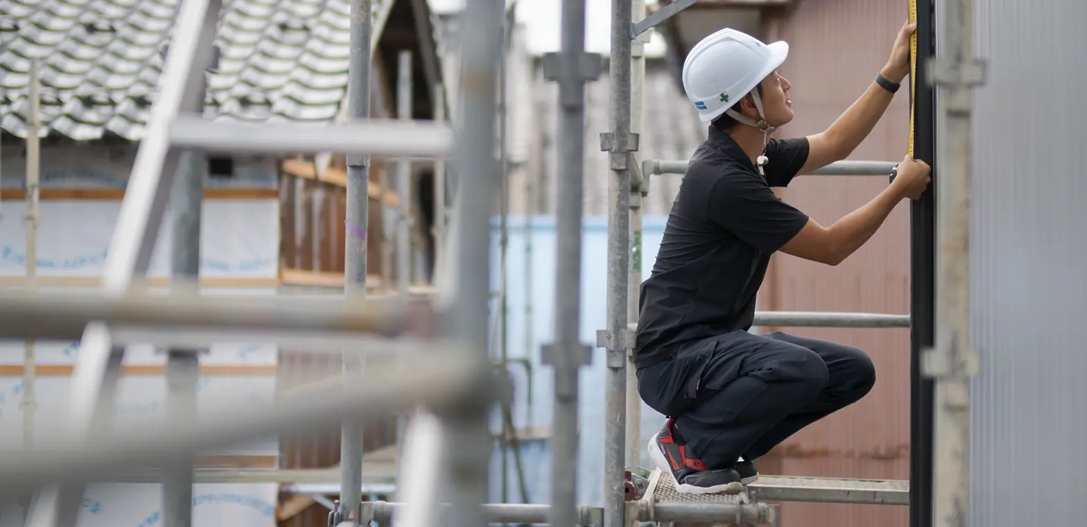 安全帯とヘルメットを着用し、足場で真剣に作業する施工スタッフ