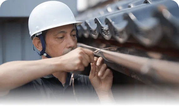 雨樋の耐久性を高めるため、熟練職人が銅線（針金）で丁寧に固定・修理を行う様子