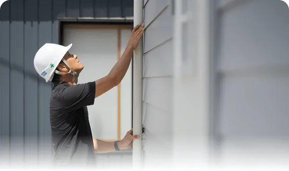 外壁に設置された縦樋（雨樋）の固定状態や詰まりを入念に確認する点検作業