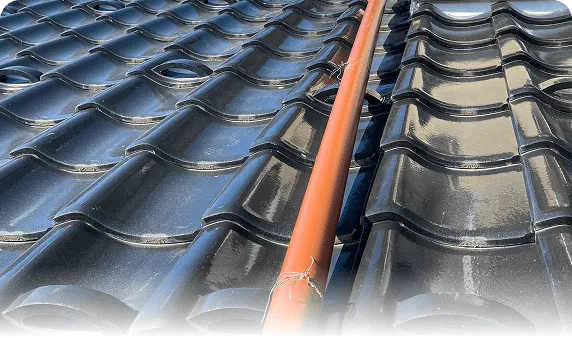 瓦屋根の上で行う屋根・雨樋工事の施工状況（配管の設置）