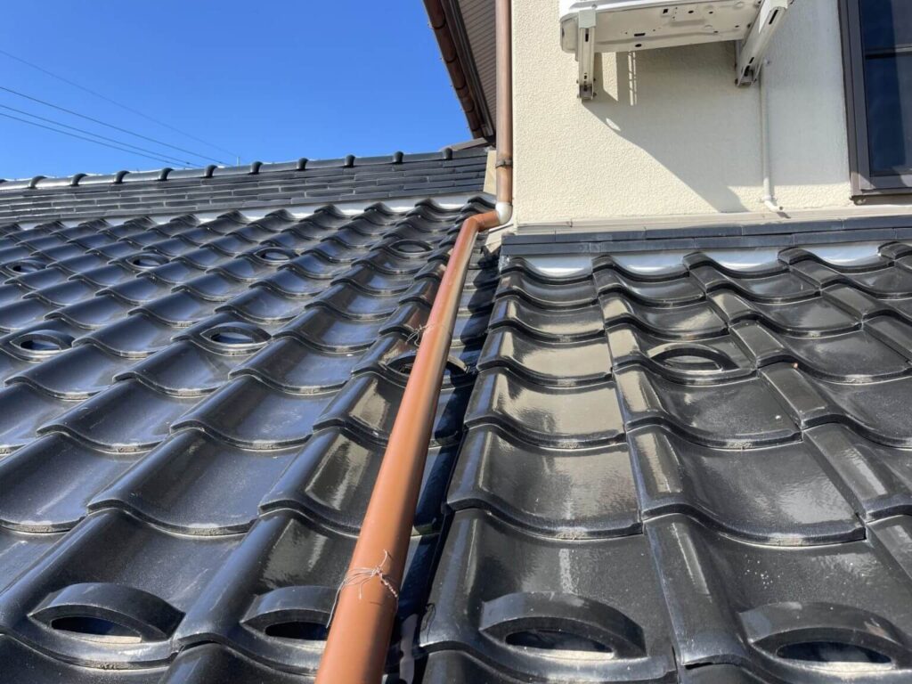 富山県八尾町で黒い瓦屋根に合わせて新しい茶色の雨樋を設置した施工後の様子
