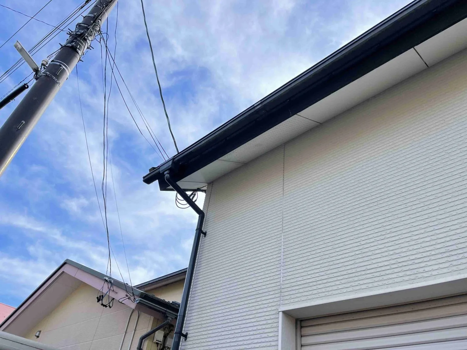 富山県射水市で白い外壁に合わせて黒い竪樋と集水器を設置した施工後の様子