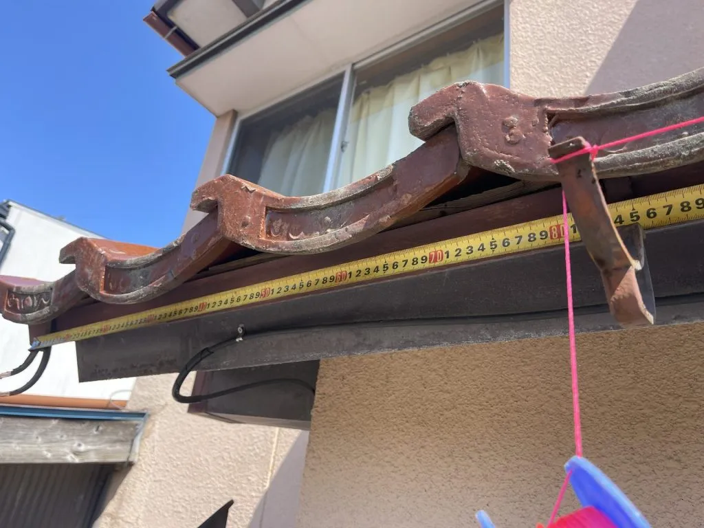新しい雨樋を取り付けるために軒先の寸法を計測している作業風景