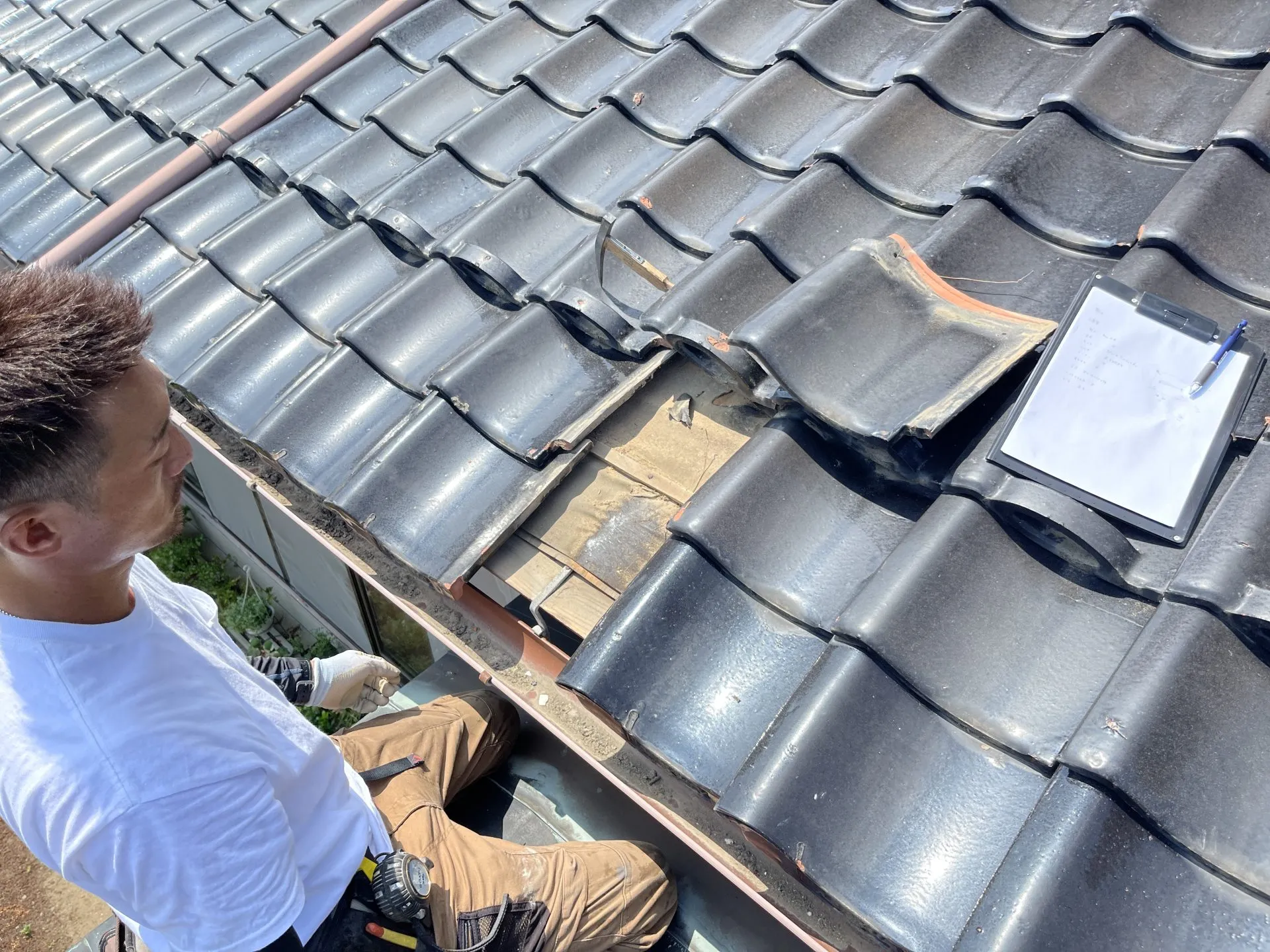 雨樋工事の見積りと瓦の状態調査をする作業員