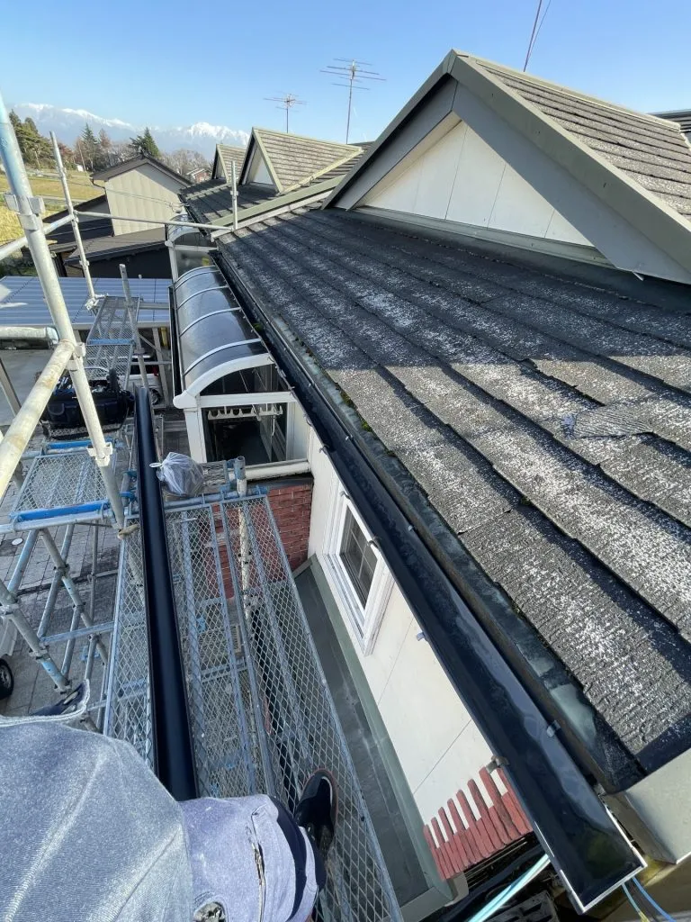 スレート屋根の形状に合わせて新しく黒い雨樋を設置した施工後の様子