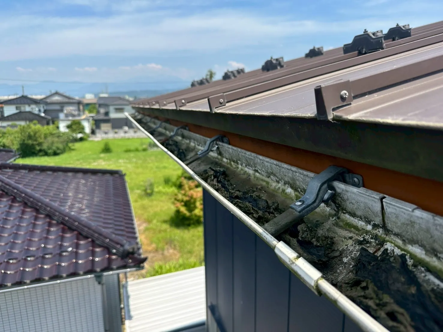 泥や苔が溜まり、詰まりを起こしている施工前の雨樋の状態