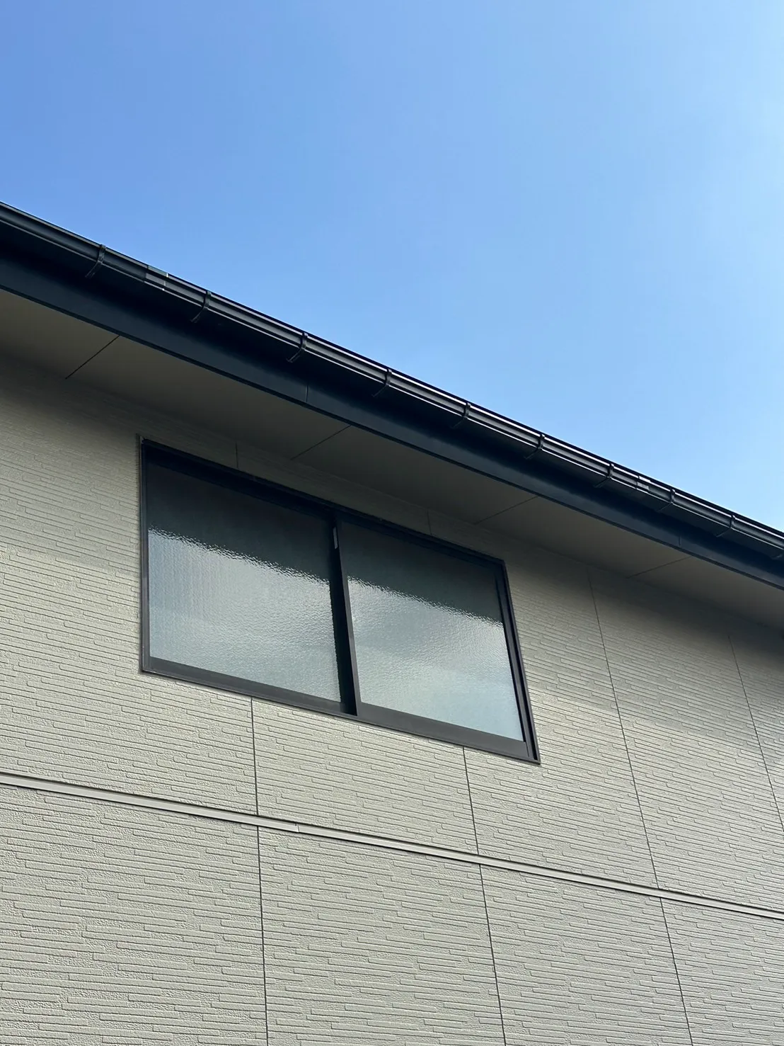 グレーの外壁に合わせて新しい黒い雨樋を設置しすっきりと仕上がった施工後の様子