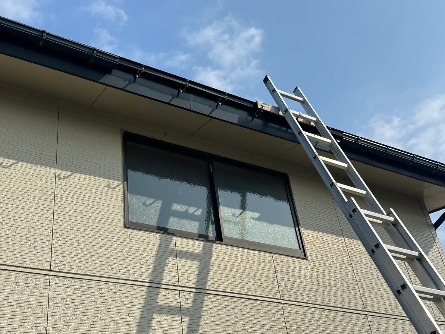 雨樋の交換修理を行うためにはしごをかけて作業の準備をしている施工前の様子