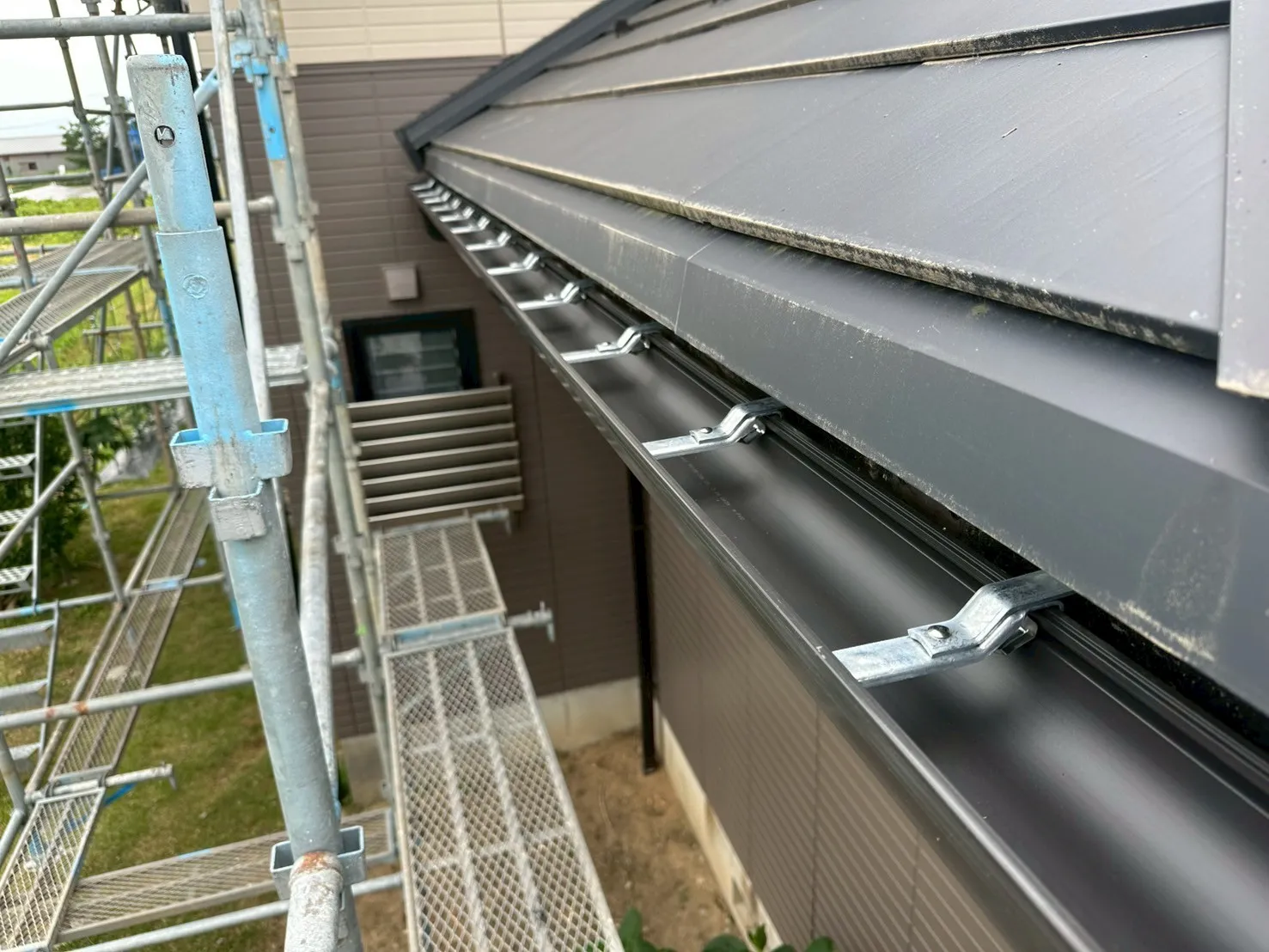 足場を設置して耐久性の高い新しい黒い雨樋へ交換した施工完了後の様子