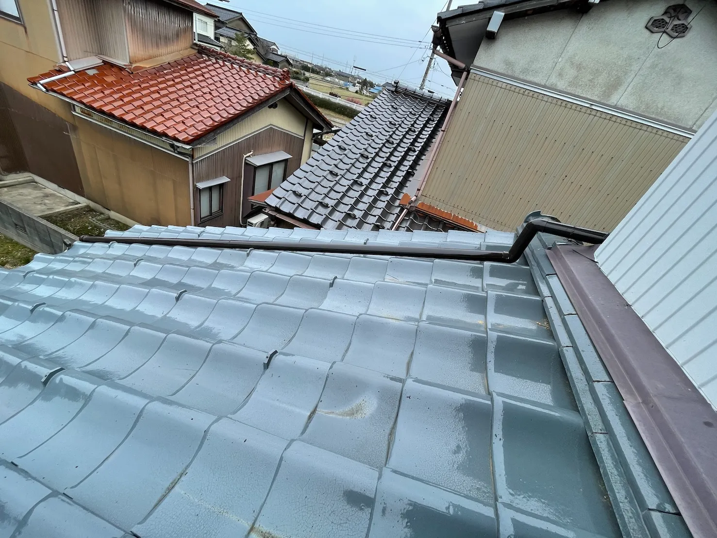 青い瓦屋根に合わせて新しく焦げ茶色の雨樋を設置した施工後の様子